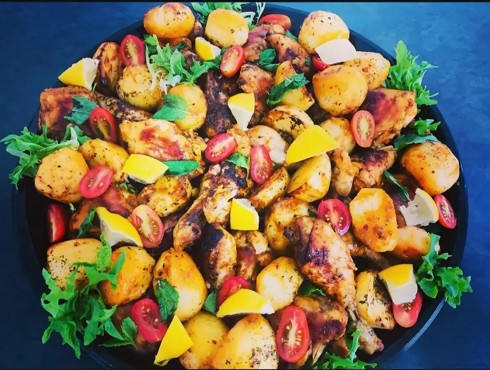 Portuguese style chicken pieces with roast potatoes, cherry tomatoes and lemon wedges